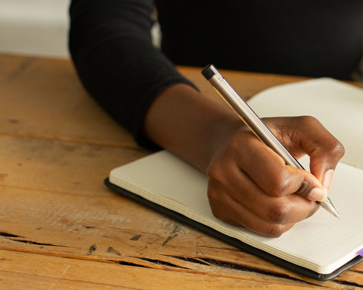 10 Must Have Clauses for your Life Coaching Contract - Woman's hand holding a pen writing in a notebook