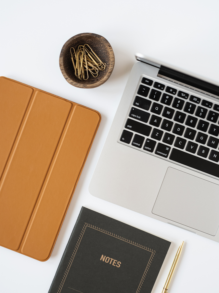5 Things You Must Include in Your Business Coaching Contract - Flatlay image of computer, tablet in a brown leather case and notebook