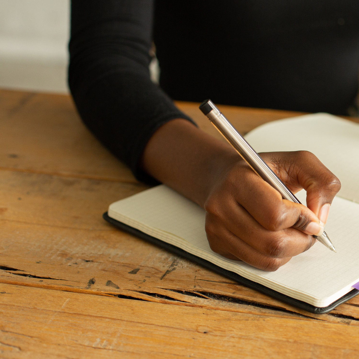 10 Must Have Clauses for your Life Coaching Contract - Woman's hand holding a pen writing in a notebook