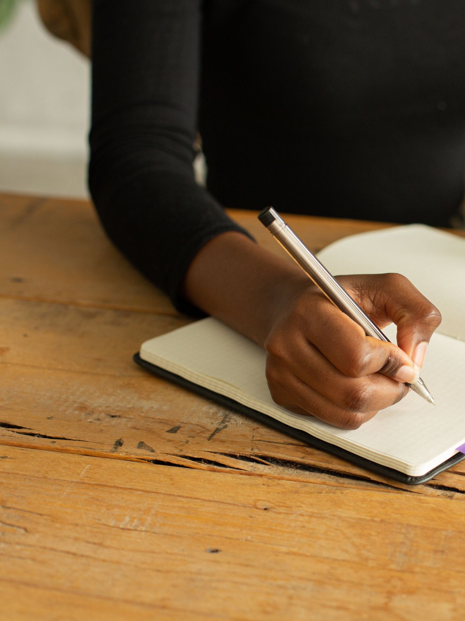 10 Must Have Clauses for your Life Coaching Contract - Woman's hand holding a pen writing in a notebook